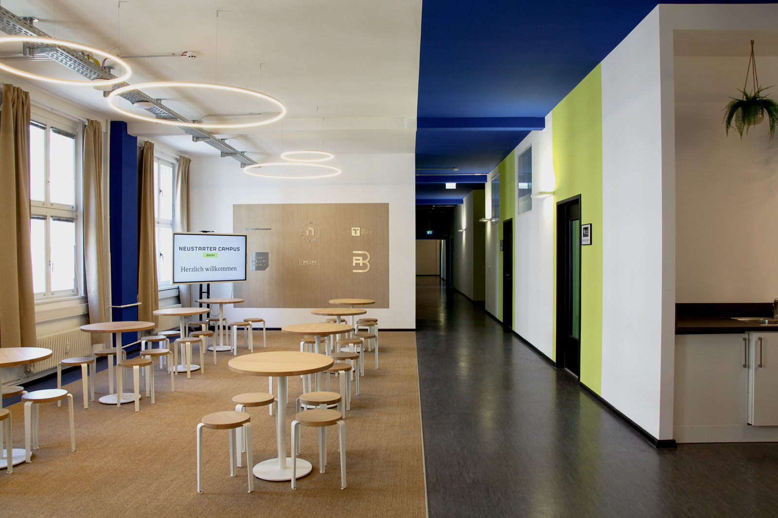Lernen vor Ort am Campus in Berlin: architektonische Aufnahme eines modernen Seminarraumes und dem anschließenden Flur