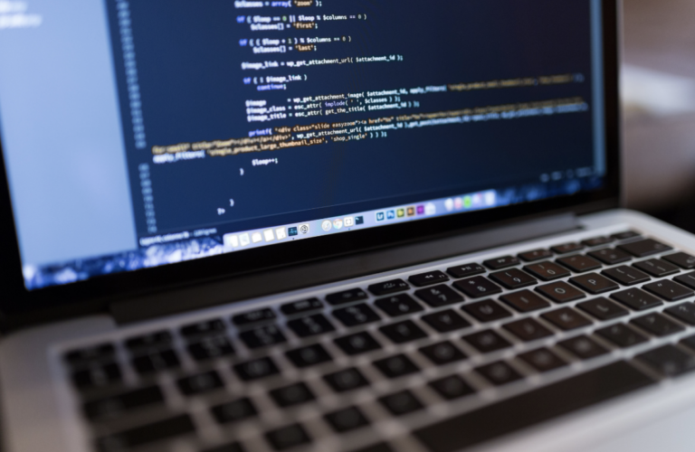 Nahaufnahme eines Laptops mit einem geöffneten Code-Editor, in dem gerade programmiert wird